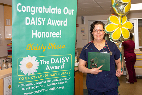 Kristy Nessa, RN, smiles with her DAISY Award and Healer’s Touch statue.