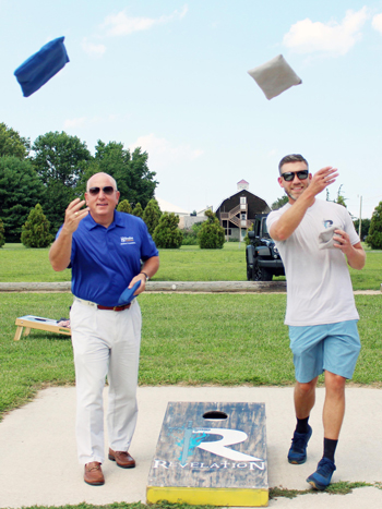 Thomas Protack, Vice President of Development, Beebe Medical Foundation, and Patrick Staggs, co-founder of Revelation Craft Brewing, toss corn hole bags outside at the Revelation Beer Garden at Hudson Fields. 