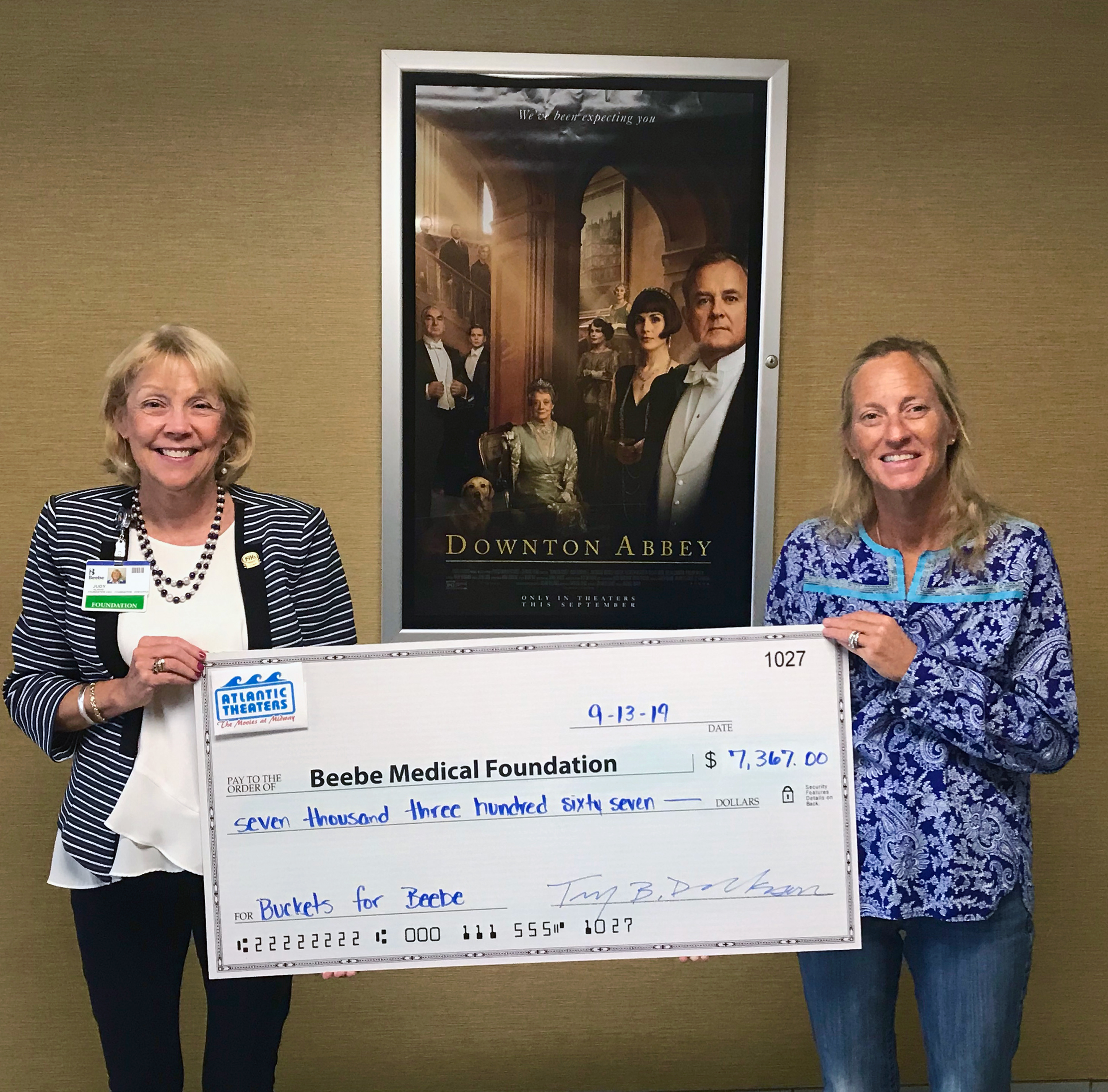 Beebe Medical Foundation President and CEO, Judy Aliquo, accepts another donation from Tiffany Derrickson, Vice President of Atlantic Theaters from the Movies at Midway “Buckets for Beebe” program.