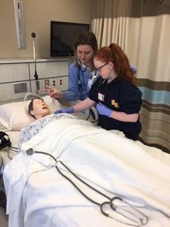 Senior student Makenzie Lee shows Girl Scout Isabella Monaghan how to count the heart rate on a manikin, Anne. 