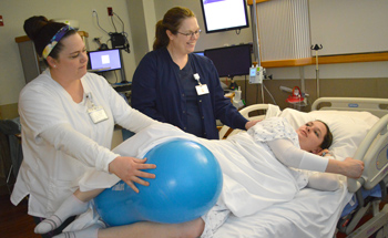 Women's Health team members help a mother use a peanut ball during labor.