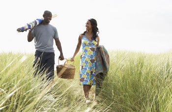 Couple walks to the beach with their picnic basket.