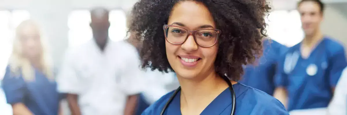 Female medical professional in scrubs with team