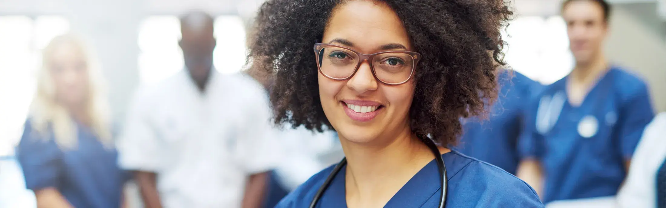 Female medical professional in scrubs with team