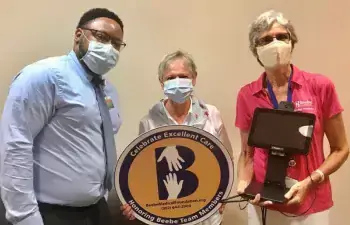 Kathee Brown celebrates the excellent care she received at Beebe Healthcare by donating a contactless temperature screening device. Shown are (l-r) Maurice Winkfield, Beebe Healthcare director of patient access; Brown; and Diane Barlow, Beebe Medical Foundation gift planning officer.