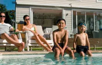 a family enjoys the sun by their pool