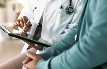 Doctor reviewing health information on tablet with patient
