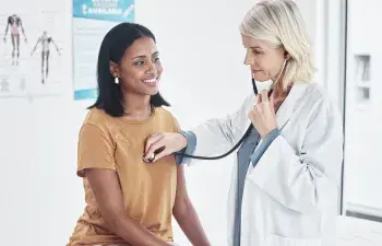 Doctor examining a woman with a stethoscope