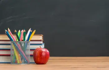 Apple on desk with colored pencils and books