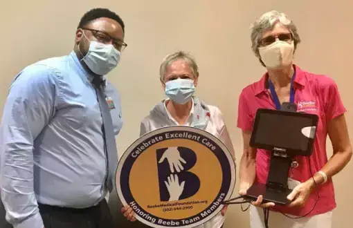 Kathee Brown celebrates the excellent care she received at Beebe Healthcare by donating a contactless temperature screening device. Shown are (l-r) Maurice Winkfield, Beebe Healthcare director of patient access; Brown; and Diane Barlow, Beebe Medical Foundation gift planning officer.
