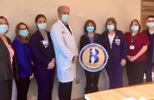 Alicia Beach (center, holding sign) celebrates excellent care at Beebe’s South Coastal Cancer Center with her care team, (l-r) Beebe Oncology Services Nurse Manager Ella-Mae Shupe, Registrar Gail Johnson, Nurse Jill Abbott, Dr. William Ryan, Nurse Michele Fletcher, CCA Brandi Denning, and Nurse Audrey Umschlag.