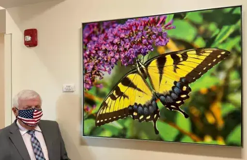 Ken Smith stands by the art he sponsored at Beebe’s new South Coastal Cancer Center in memory of his wife. The plaque reads “Yellow Swallowtail by Ron Bojarski Sponsored by Kenneth P. Smith in Memory of Denise Michele Smith, Loving Wife and Mother.”