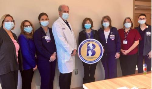 Alicia Beach (center, holding sign) celebrates excellent care at Beebe’s South Coastal Cancer Center with her care team, (l-r) Beebe Oncology Services Nurse Manager Ella-Mae Shupe, Registrar Gail Johnson, Nurse Jill Abbott, Dr. William Ryan, Nurse Michele Fletcher, CCA Brandi Denning, and Nurse Audrey Umschlag.